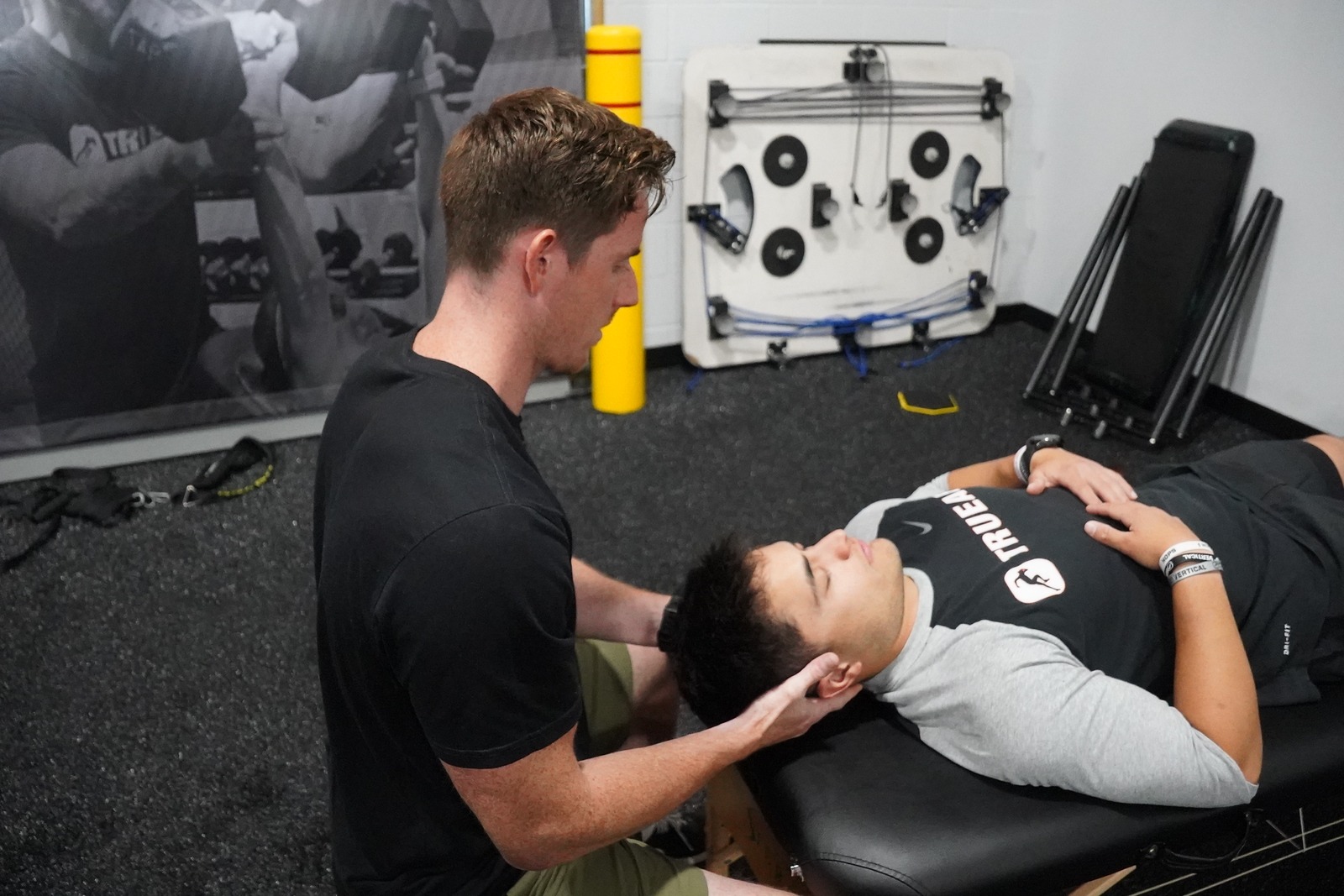 A physical therapist checks a patient’s head during an exam.