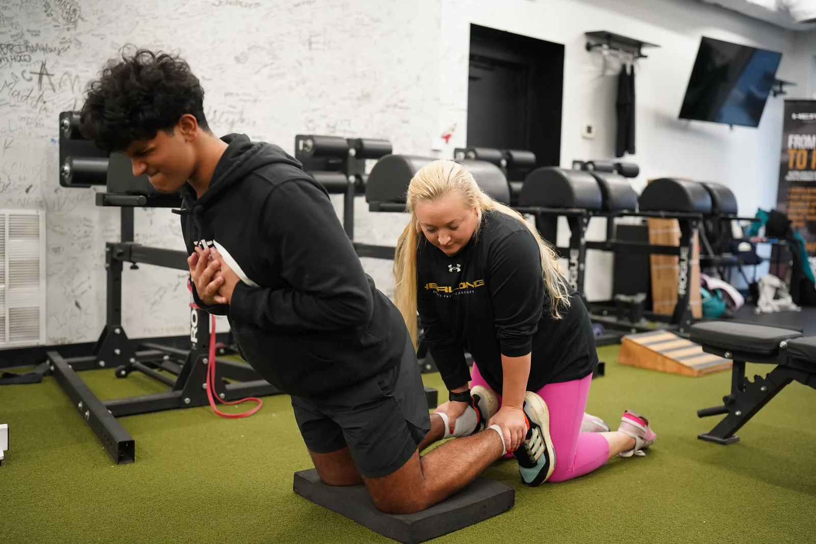 A physical therapist holds the legs of a patient while they perform a core exercise.